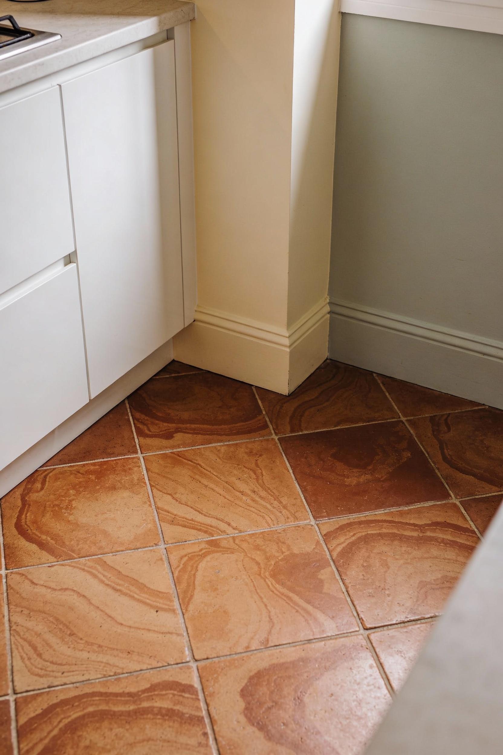 Warm terracotta floor tile kitchen with light walls to open up the room